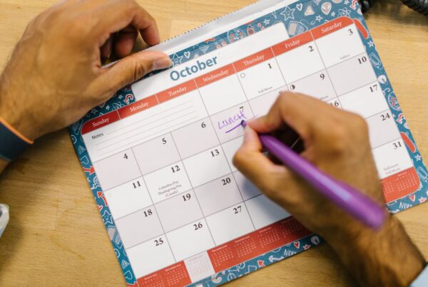 A person writing a reminder on a monthly calendar