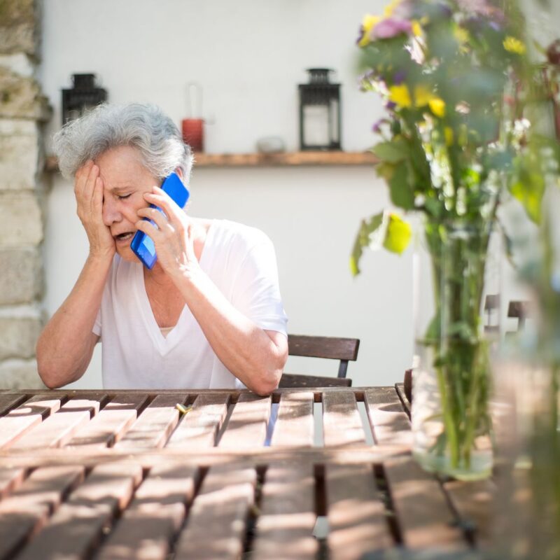 A distressed woman holding a mobile phone outdoors