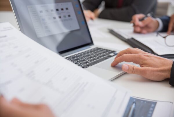Two people reviewing documents beside a laptop